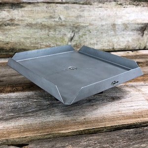 May include: A square metal tray with a slightly raised edge. The tray is made of a light gray metal and has a small hole in the center.