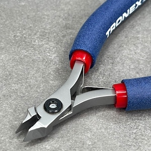 May include: Close-up of a pair of blue and red handled wire cutters with the brand name TRONEX printed on the handle. The cutters have a sharp, angled blade.