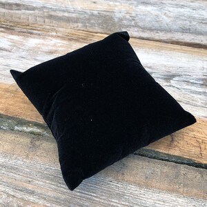 May include: A black velvet cushion, ideal for displaying jewellery or other small items.