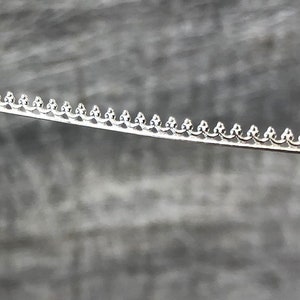 May include: Silver trim with a decorative scalloped edge.