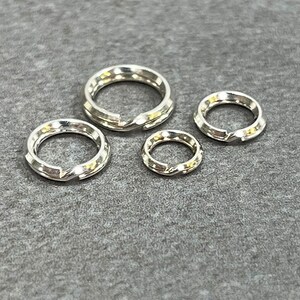 May include: Four silver jump rings of different sizes. The rings are smooth and shiny.