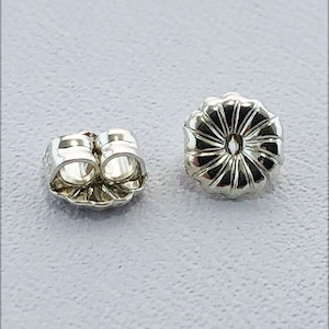 May include: Two silver earring backs, one is a butterfly back and the other is a standard push back.