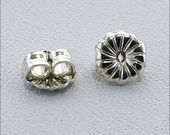 May include: Two silver earring backs, one is a butterfly back and the other is a standard push back.
