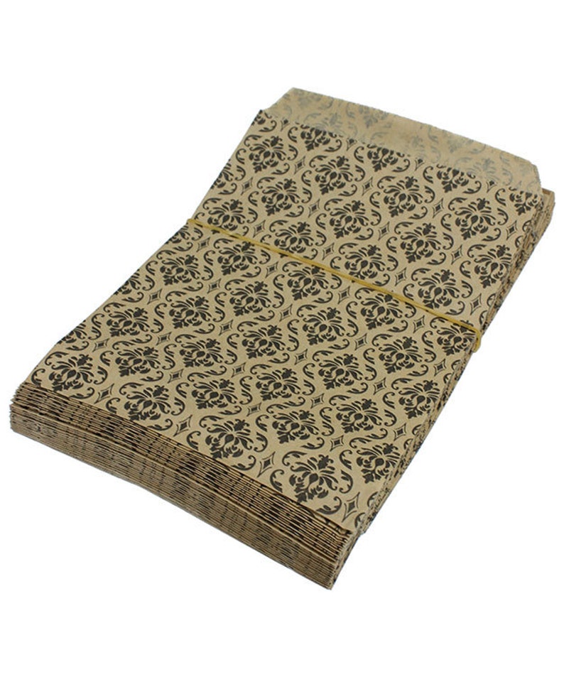May include: A stack of brown paper bags with a black damask pattern. The bags are tied together with a rubber band.