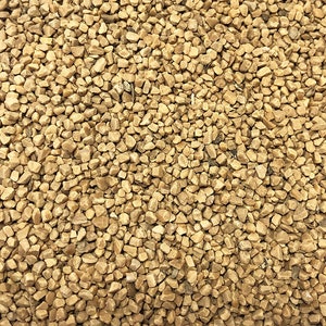 May include: Close-up of a pile of small, light brown, irregularly shaped pieces of granulated sugar.