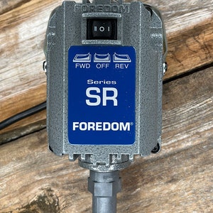 Puede incluir: Un motor el&eacute;ctrico de metal gris con una etiqueta azul que dice "FOREDOM" y "Series SR". El motor tiene un interruptor con las etiquetas "FWD", "OFF" y "REV".