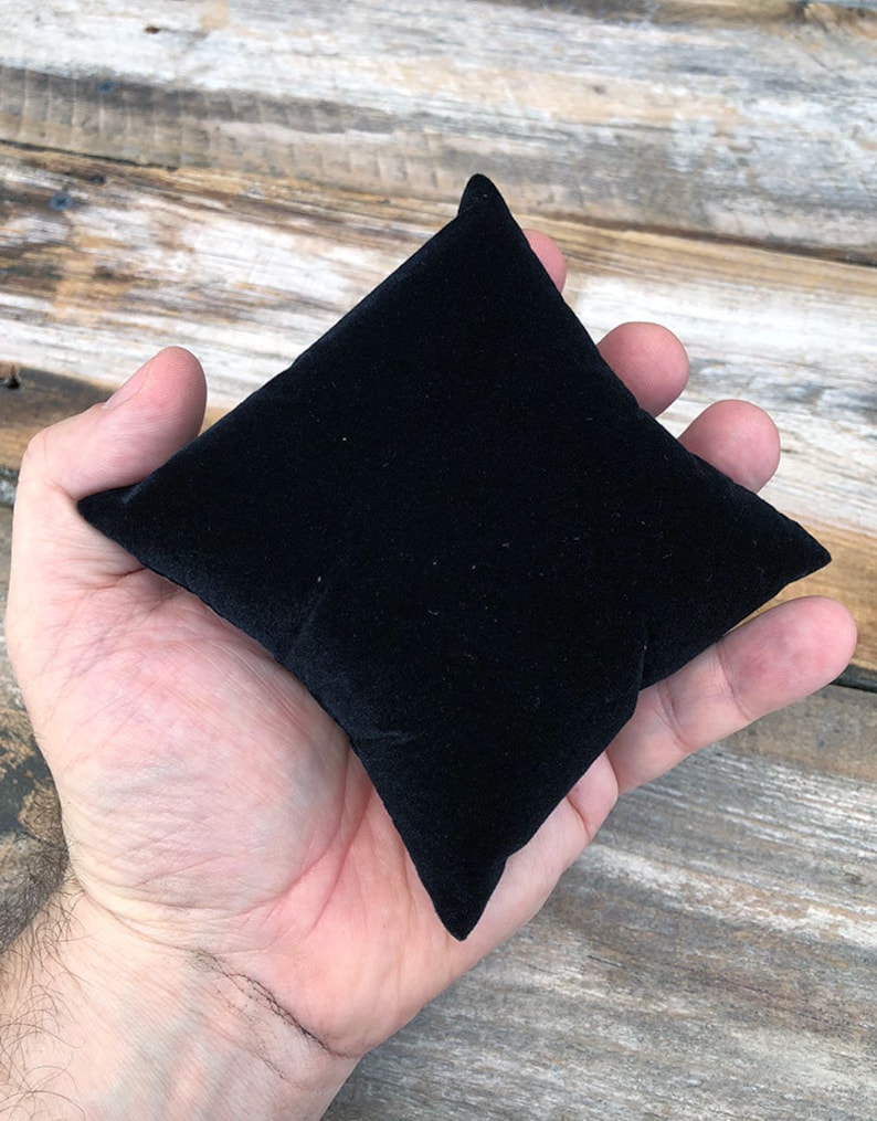 May include: A small, black velvet cushion, ideal for displaying jewellery or other small items.