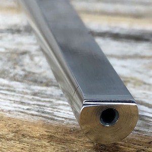May include: Close-up of the end of a silver metal rod with a small hole in the center.