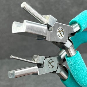May include: A pair of silver-toned jewelry pliers with turquoise handles. The pliers have a unique design with a small, square-shaped head and a long, thin arm. The pliers are used for making jewelry.