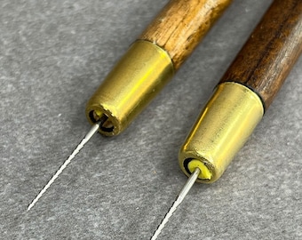 May include: Two wooden handled tools with brass tips and a thin, twisted metal needle extending from each tip.