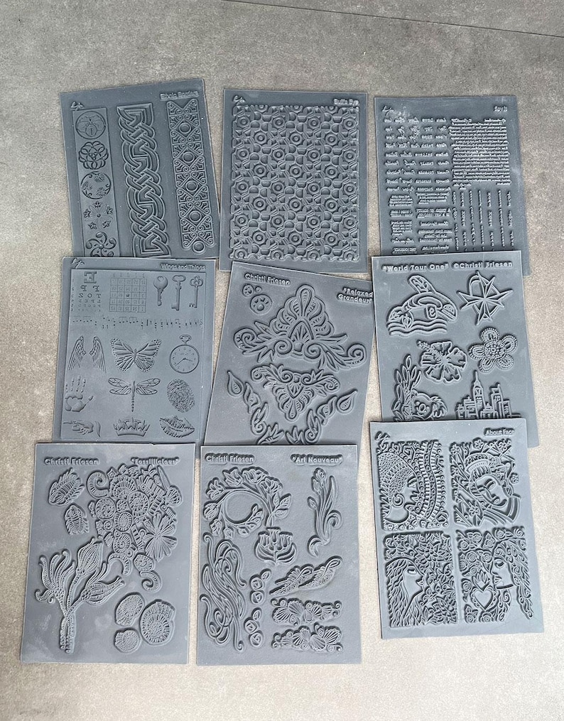 May include: Set of ten black and gray rubber stamps with various designs, including floral patterns, geometric shapes, and text. The stamps are arranged in two rows of five. The text on the stamps includes "World Tour Craft" and "Chalk It Up".