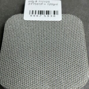 May include: A gray, square-shaped filter with a textured surface. The filter has a white label with the text "mfg # 110125 ST7681P = 120g/nt" and a barcode with the number "0007 5930".