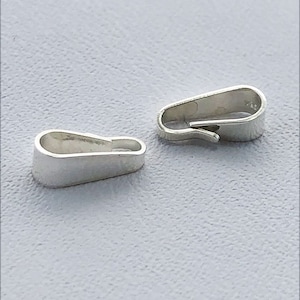 May include: Two silver-toned metal clasps for jewelry making. The clasps are oval-shaped and have a smooth, polished finish.