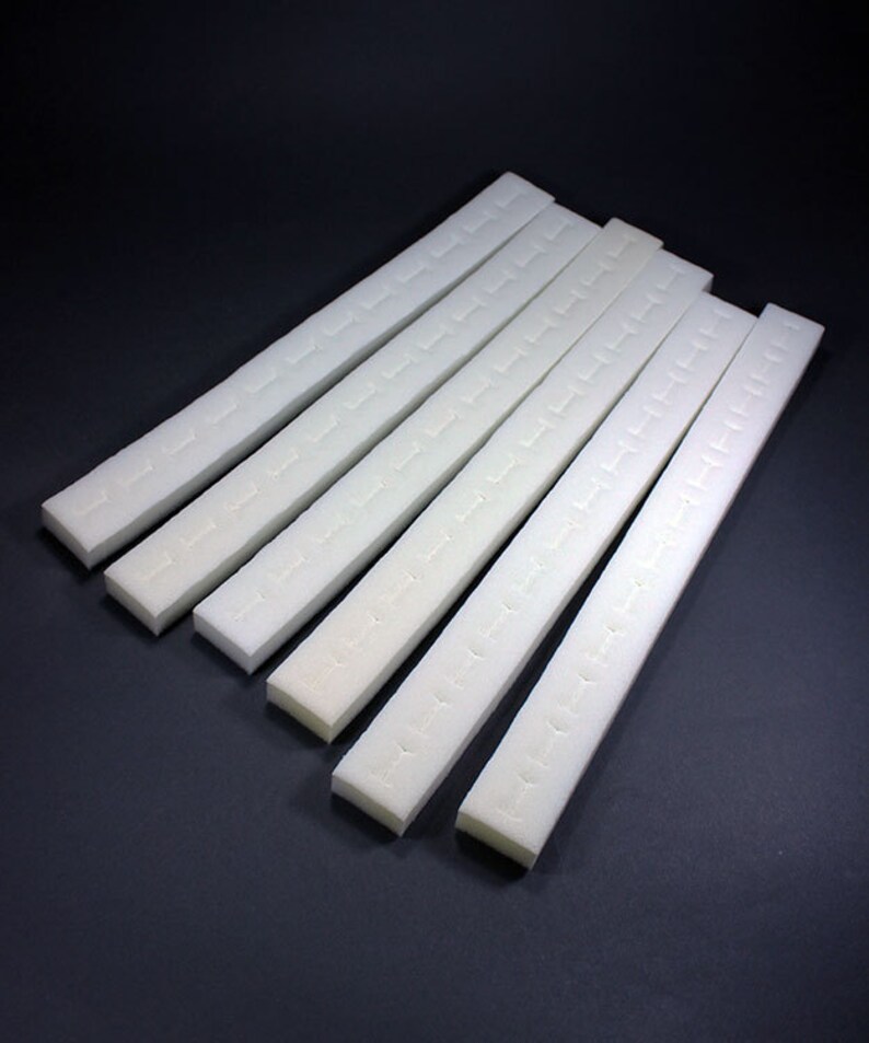 May include: Eight white foam strips with adhesive backing. The strips are about 12 inches long and have a textured surface.