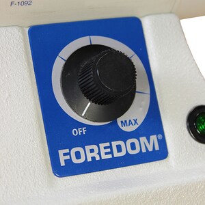 Może przedstawiać: Niebieski panel sterowania z pokrętłem, kt&oacute;re można obracać, aby regulować prędkość narzędzia obrotowego Foredom. Pokrętło jest oznaczone jako "OFF" i "MAX".