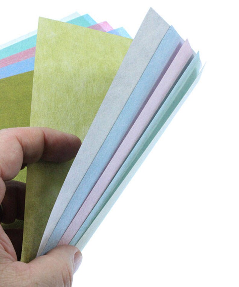 May include: A stack of colorful paper sheets in shades of green, blue, pink, and white. The paper is textured and has a slightly rough surface.