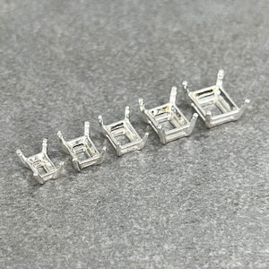 May include: Six silver-toned metal settings for bezel settings for gemstones. The settings are arranged in order of size, with the smallest on the left and the largest on the right.