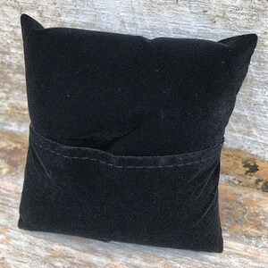 May include: A black velvet cushion with a small pocket sewn into the front.
