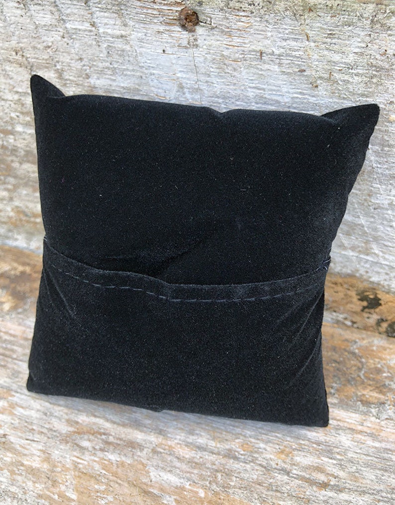 May include: A black velvet cushion with a small pocket sewn into the front.