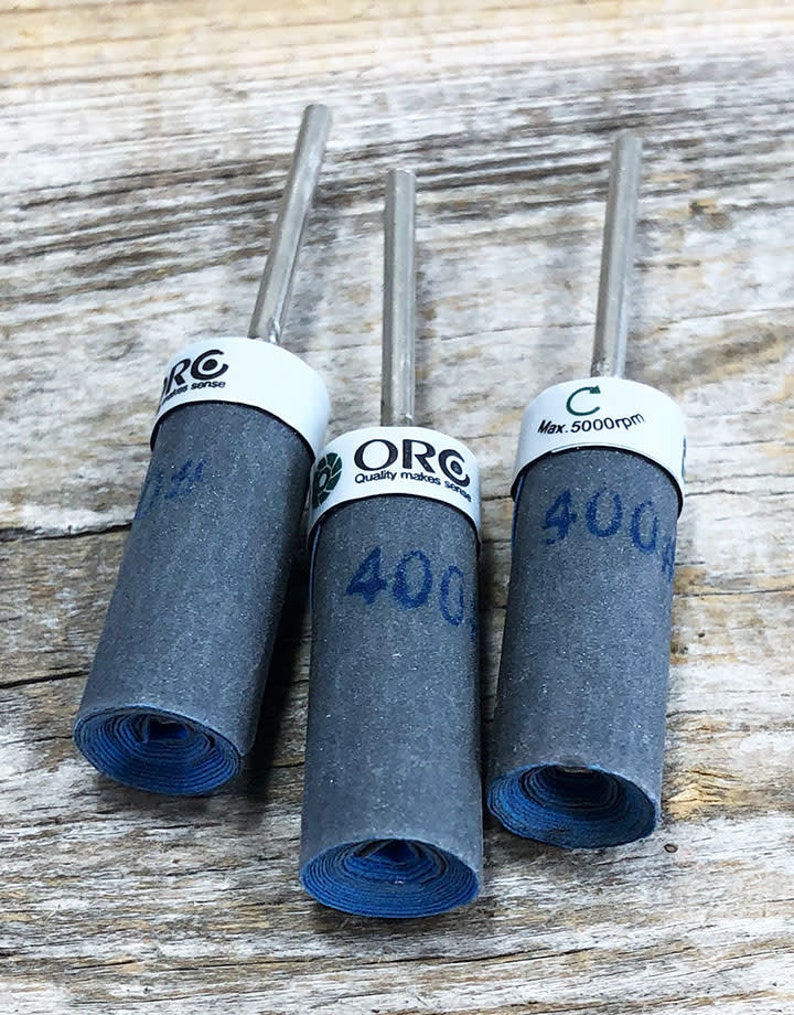 Może przedstawiać: Trzy szare bębny szlifierskie z niebieskimi krawędziami i srebrnym metalowym wałem. Bębny są oznaczone tekstem "ORC Quality makes sense" i "400". Trzeci bęben jest oznaczony "C Max. 5000rpm" i "400".