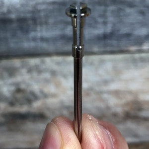 Pu&ograve; includere: Primo piano di uno strumento in metallo argentato con un'estremit&agrave; divisa. Lo strumento &egrave; tenuto in una mano.