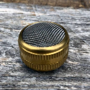 May include: A gold-colored metal filter with a fine mesh screen. The filter is designed for use with a smoking pipe.