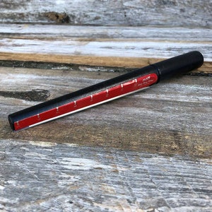 May include: A black ring sizer with a red and white measuring tape. The sizer is marked with sizes from 5 to 11.