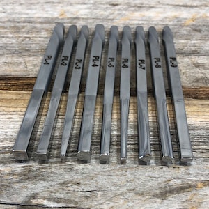 May include: Nine metal tools with different shaped tips, labeled PL-1 through PL-9, arranged in a row on a wooden surface.