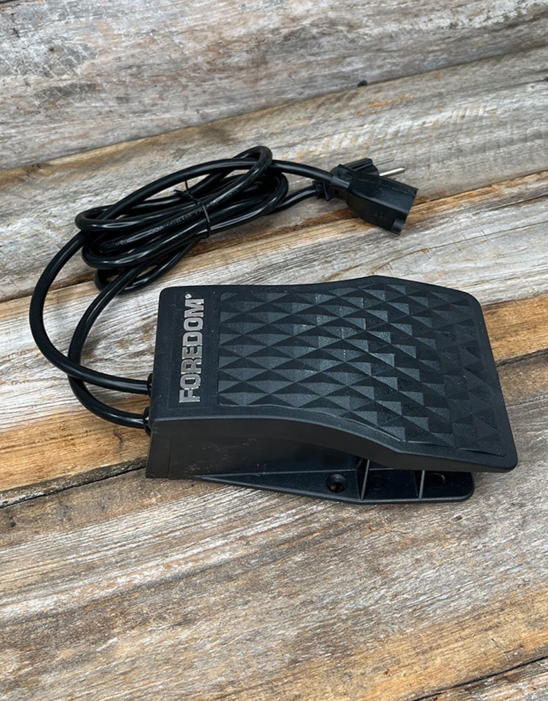 Puede incluir: Pedal de pie negro con un patr&oacute;n de diamante en la parte superior. El pedal tiene un cable negro con un enchufe europeo. El texto "FOREDOM" est&aacute; impreso en el lateral del pedal.