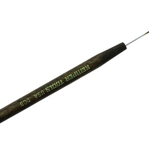 May include: A brown wooden handled tool with a thin metal hook at the end. The handle is labeled "KEMPER TOOLS USA DOS".
