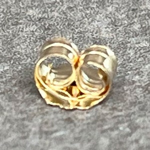 May include: Gold-toned earring back with a secure, spring-loaded closure.