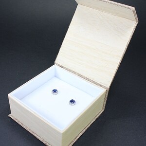 May include: A small wooden box with a hinged lid, lined with white velvet, and containing two blue sapphire earrings.
