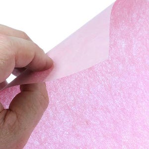 May include: A sheet of pink tissue paper with a subtle textured pattern. The paper is translucent and has a slightly crinkled appearance.