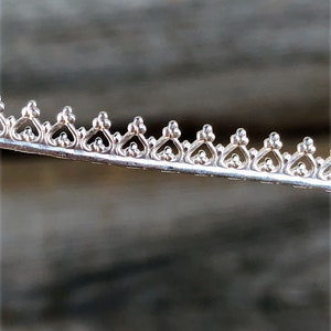 May include: Close-up of a silver trim with a decorative pattern of repeating heart shapes.