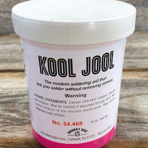 May include: A pink plastic bottle of Kool Jool soldering aid. The bottle is labeled with the product name, a warning about potential skin and eye irritation, and the product number 54.468. The bottle is 8 ounces.
