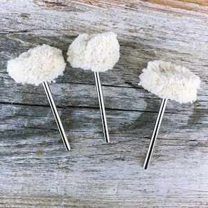 May include: Three white cotton buffing wheels attached to metal shafts. The buffing wheels are used for polishing and sanding.