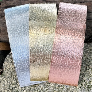 May include: Three rectangular metal sheets in silver, gold, and copper colors. Each sheet has a textured, mosaic-like pattern across its surface. The sheets are arranged side by side, with the silver sheet on the left and the copper sheet on the right.