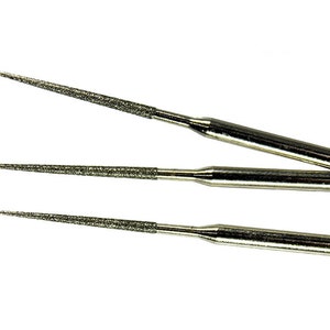 May include: Three silver diamond burrs with a textured surface. The burrs are different lengths and have a pointed tip.