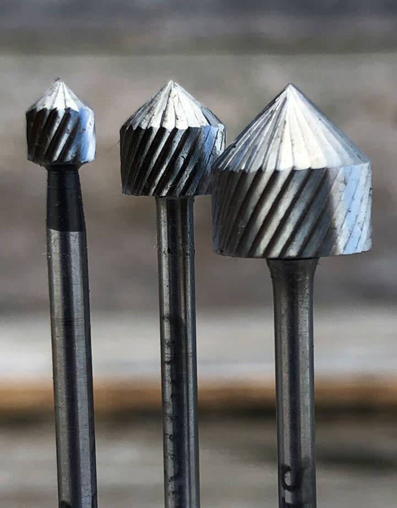 Pu&ograve; includere: Tre frese rotative in metallo argentato di diverse dimensioni. Le frese hanno una punta appuntita e un design a spirale.