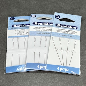 May include: Three packages of Beadalon collapsible eye needles. The packages are labeled with the needle size: Fine, Medium, and Heavy. Each package contains four needles and is labeled with the text "4 pc/pz".