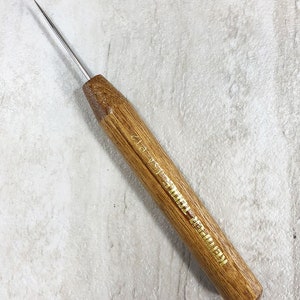 May include: A wooden tool with a thin, pointed metal tip. The tool has a gold inscription that reads "1/2 pt."