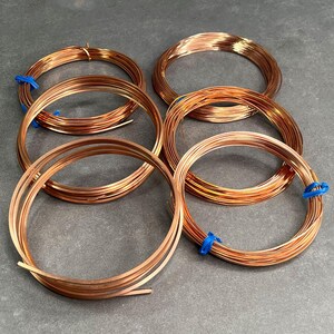 May include: Six spools of copper wire, each wrapped in blue tape. The wire is a shiny, reddish-brown color.