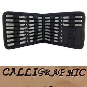 May include: A black case containing a set of metal letter stamps. The stamps are arranged in rows and labeled with the alphabet. Below, the words "CALLIGRAPHIC UPPER CASE" are stamped into a brown surface, showcasing the font style.