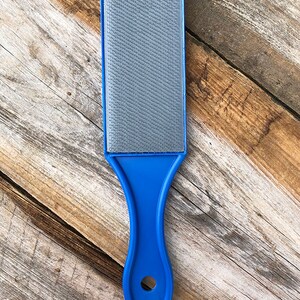May include: A blue handled gray sanding block with a textured surface.