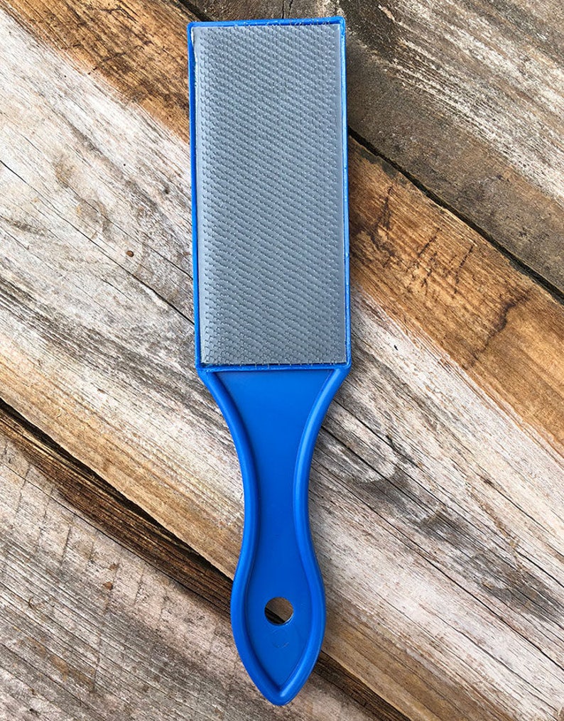 May include: A blue handled gray sanding block with a textured surface.