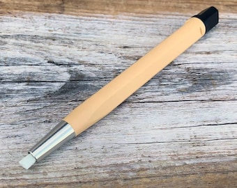 May include: A close-up of a beige and silver cleaning tool with a black tip. The tool is designed for cleaning delicate surfaces.