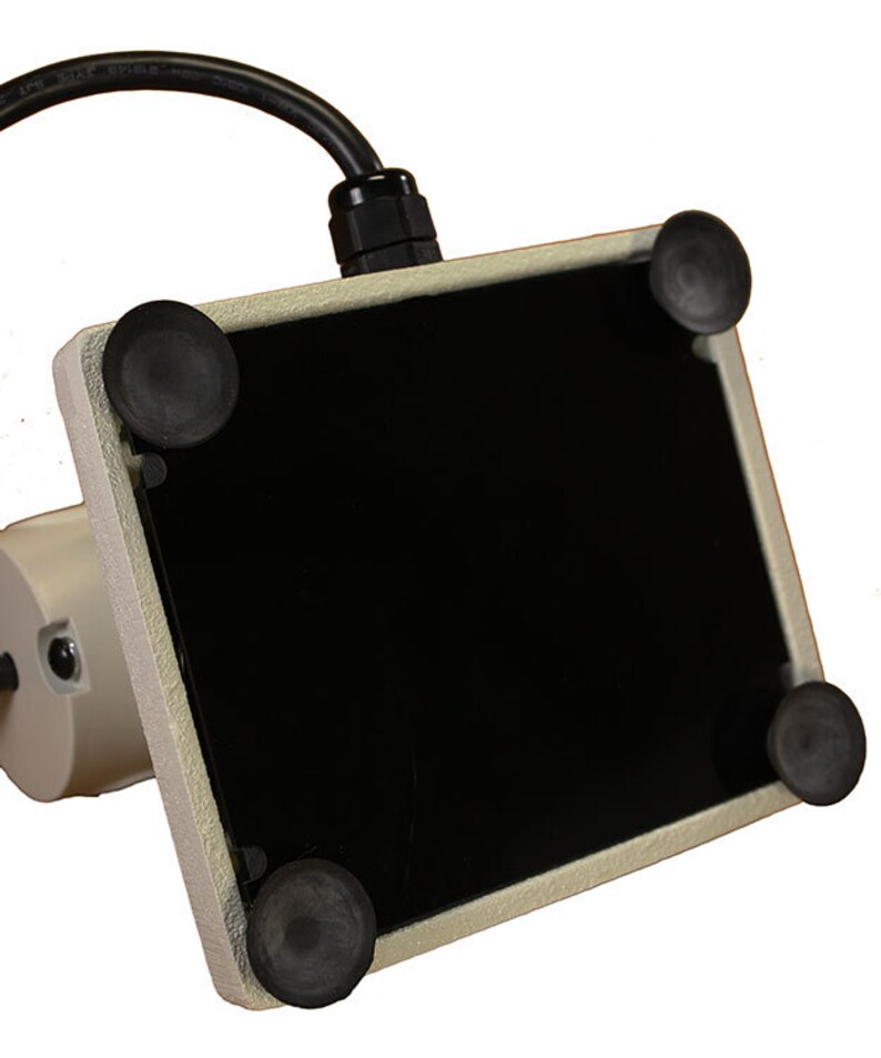 Może przedstawiać: Biała podstawa z czarną powierzchnią i czterema gumowymi stopkami na spodzie. Podstawa ma przymocowany kabel.