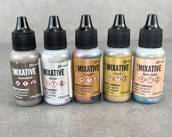 May include: Five bottles of Mixative metallic liquid in Gunmetal, Silver, Copper, Gold, and Rose Gold colors. Each bottle has a black cap and a label with the product name and hazard warnings. Each bottle contains 5 fl oz (14 ml).