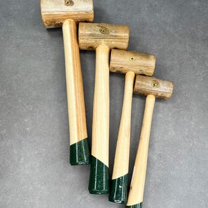 May include: Four wooden mallets with green painted handles. The mallets are different sizes and are arranged in a row from largest to smallest.
