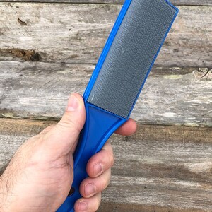 May include: A blue plastic hand-held file with a gray abrasive surface.